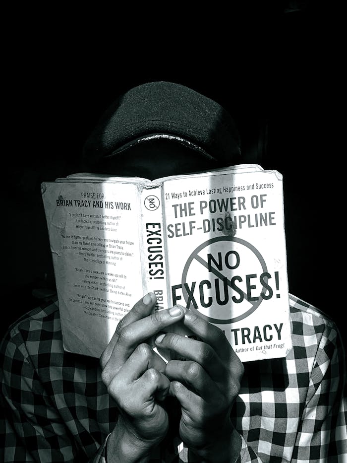 Black and white photo of a person reading a book on self-discipline, highlighting focus and learning.